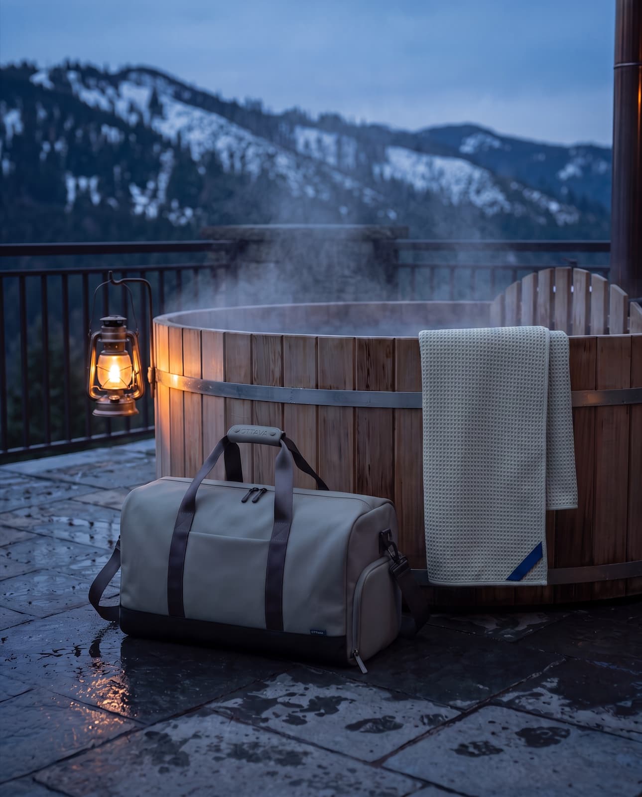 Duffel 50 by a steaming outdoor tub on a mountain chalet terrace at dusk