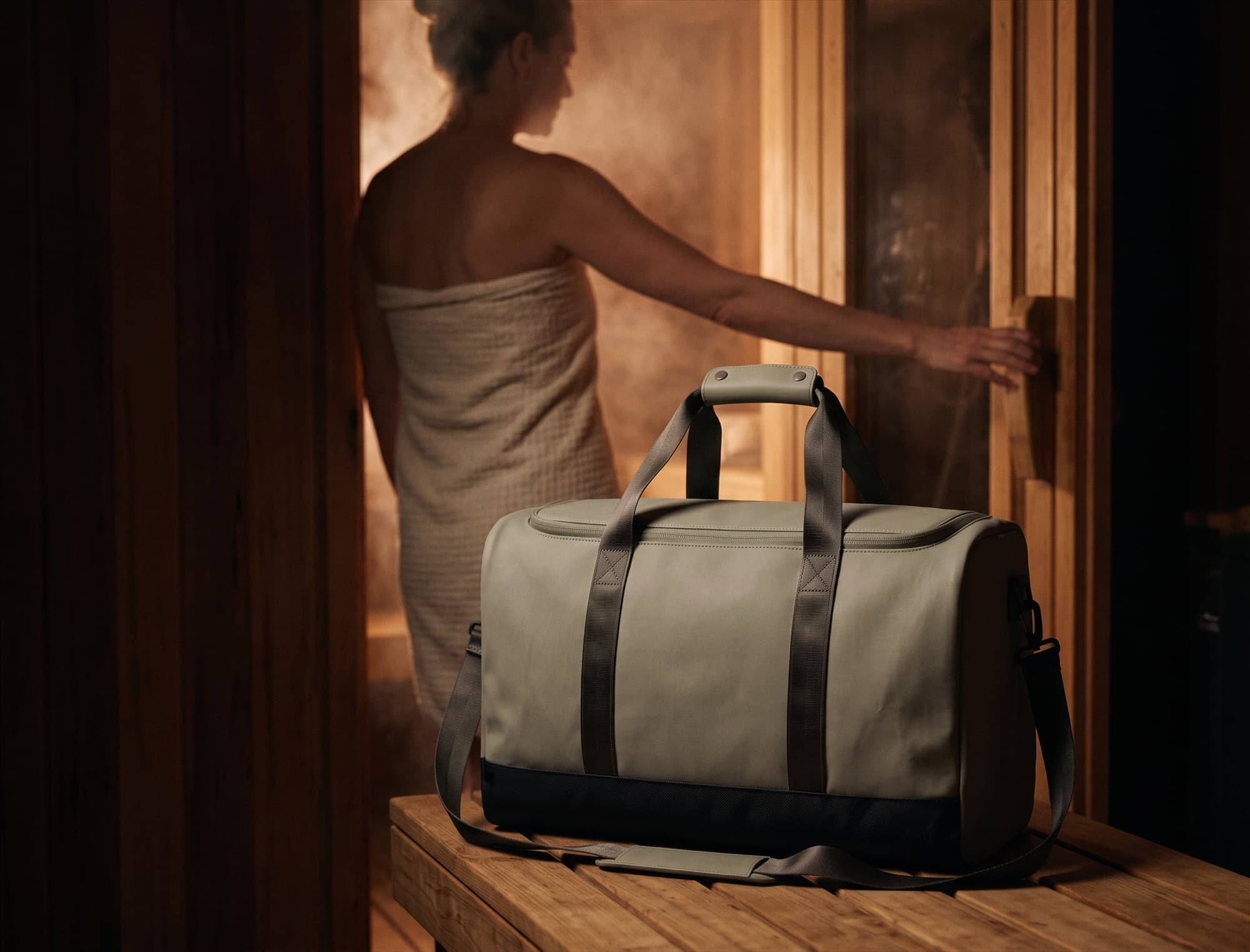 At the door of a cedar sauna, bag on the bench behind