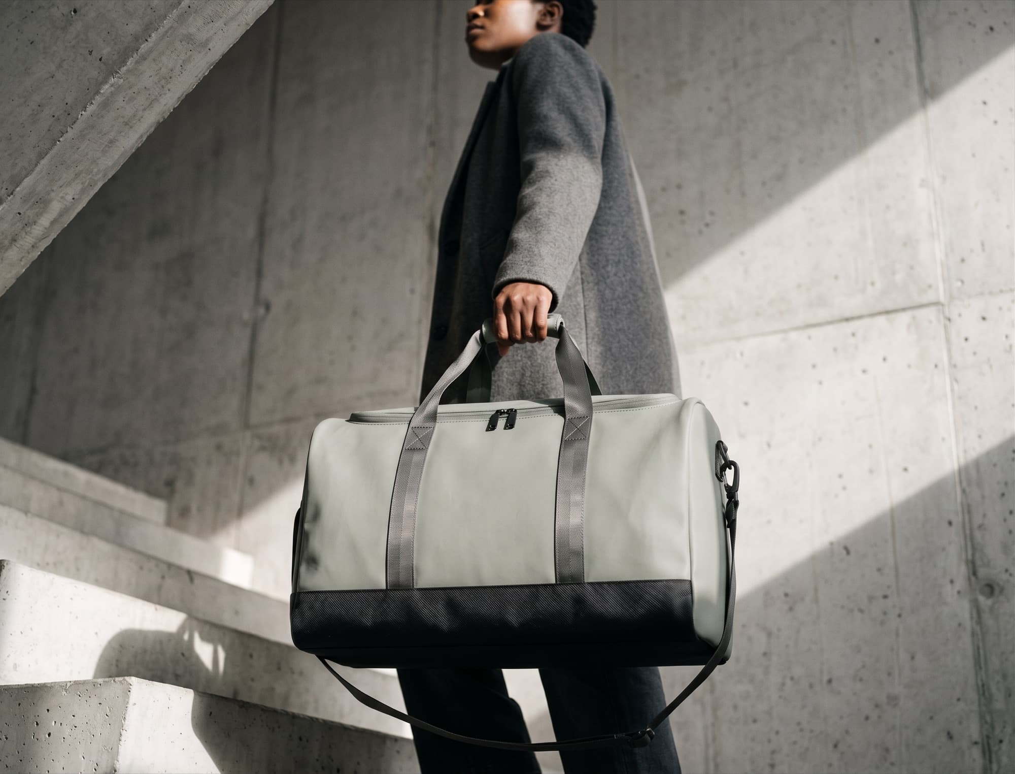 Carrying the duffel by the handles up a concrete stairwell